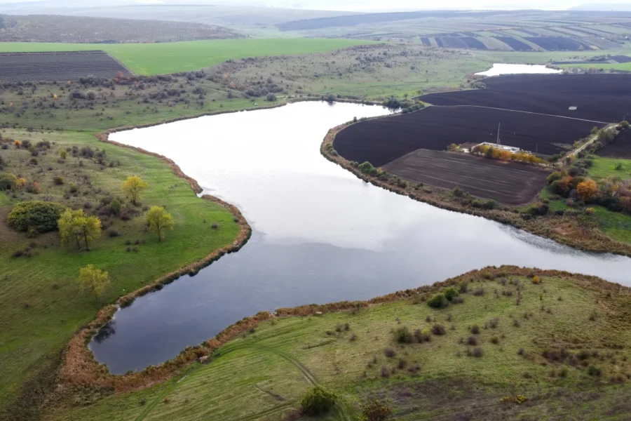 aerial-drone-view-nature-moldova-lake-with-cloudy-sky-reflecting-sown-fields-trees